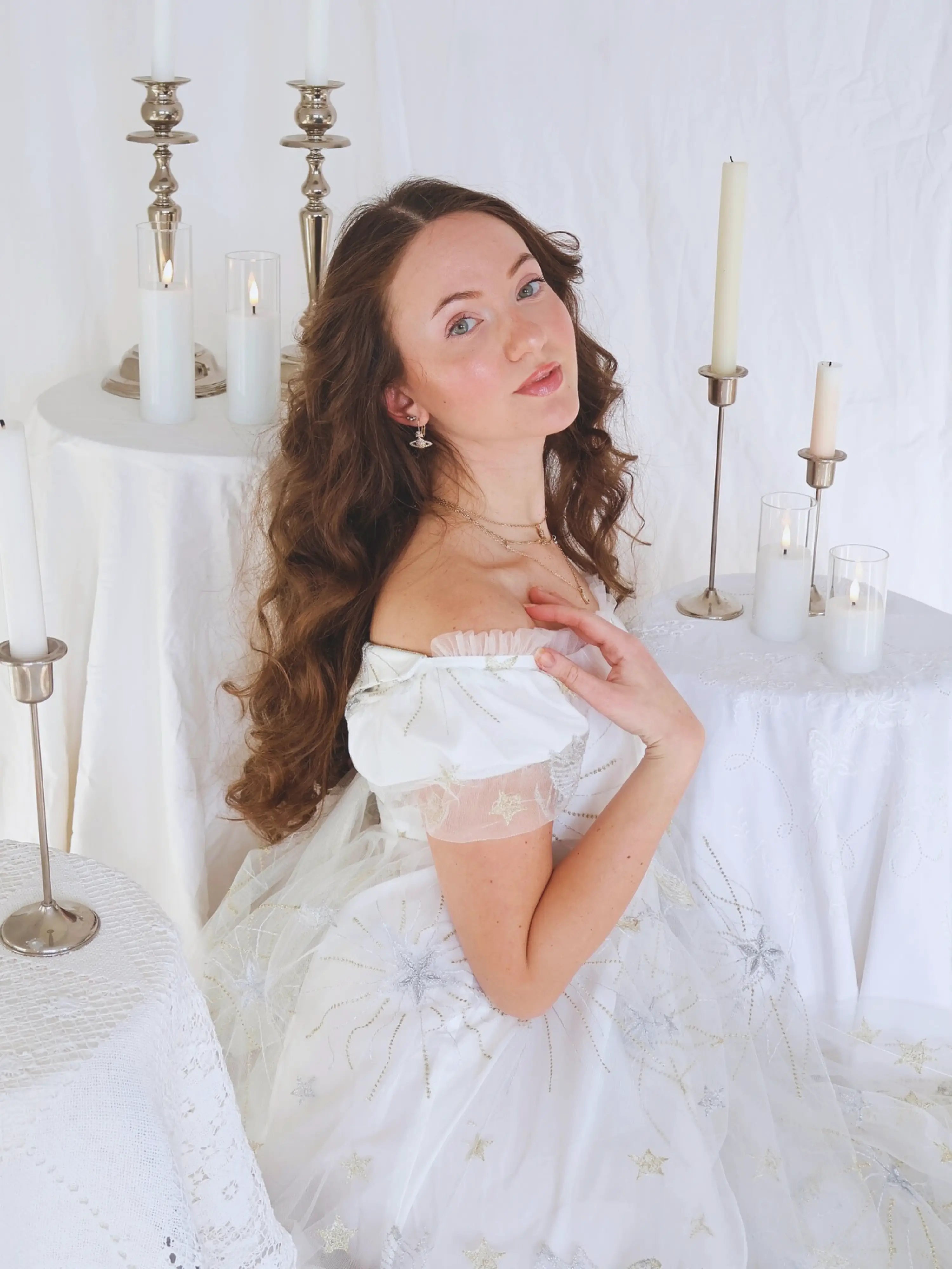 Influencer jmaclaren stuns in the celestial veil dress in a romantic setting surrounded by candles and linens.