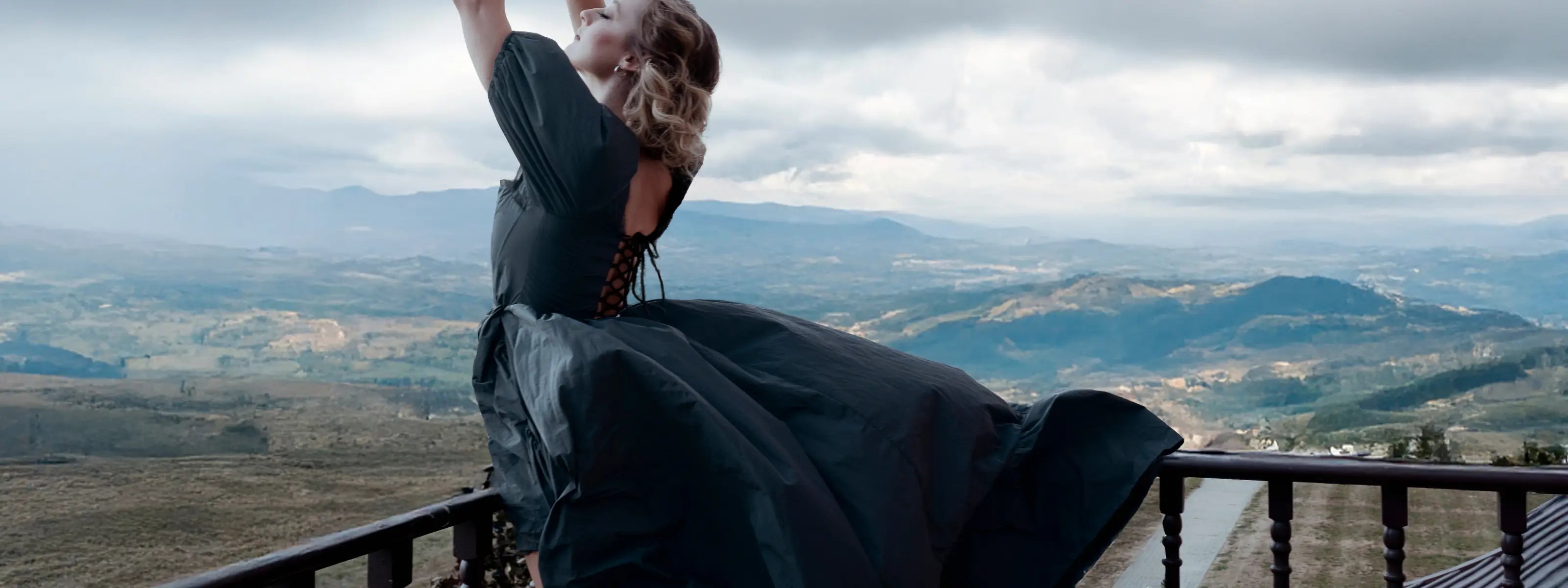 A woman wearing a black corset dress on a balcony