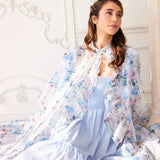 Alice Blue Josephine Midi Dress paired with a floral sheer cape, showcasing soft coquette fashion. Blue midi dress styled for romantic elegance.