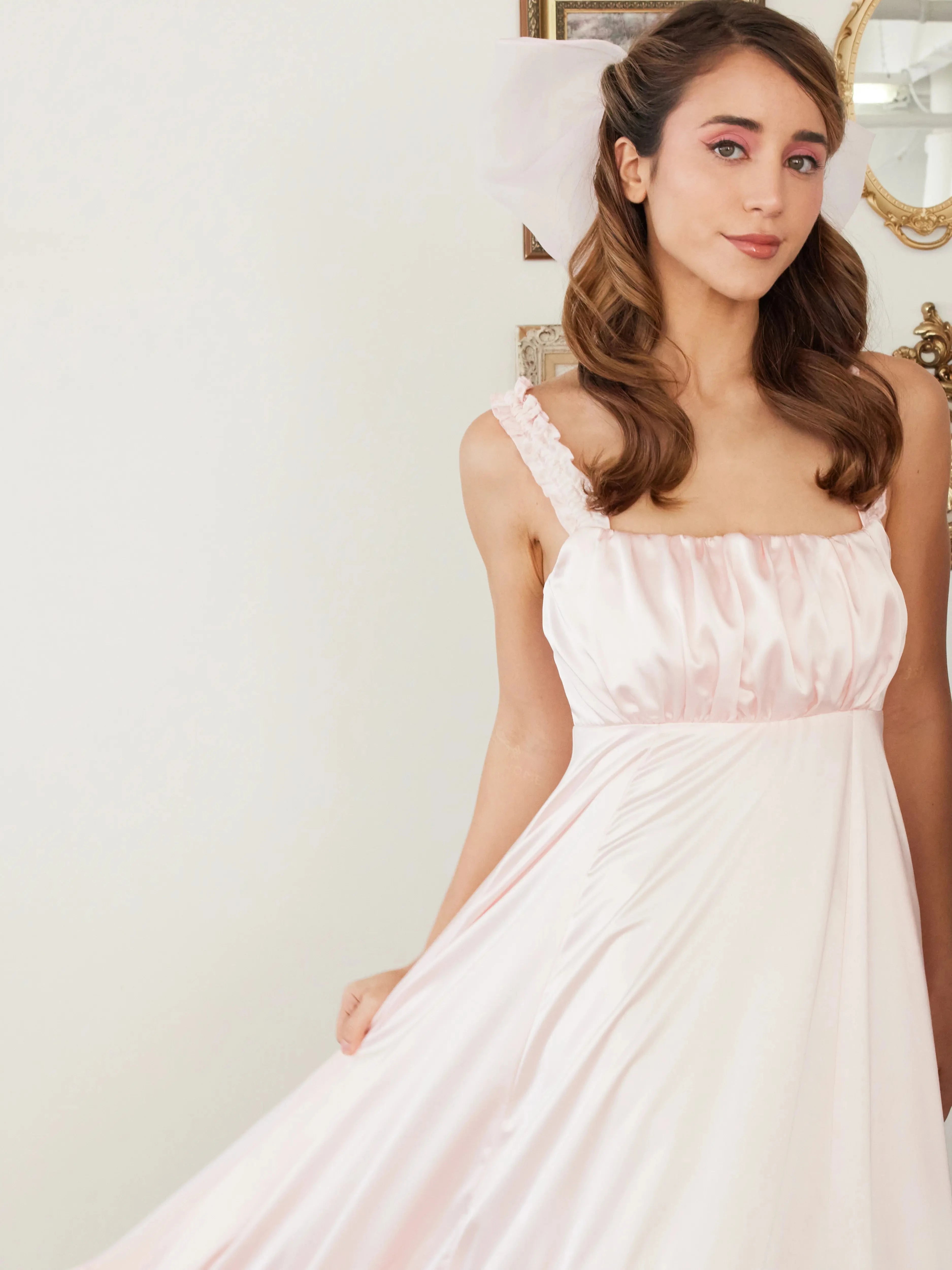 Ballerina Pink Satin Midi Dress featuring ruched straps and flowing satin fabric, styled with soft curls and pink makeup for a dreamy look.