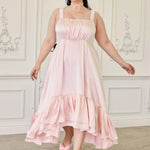 Ballerina Pink Satin Midi Dress with high-low ruffled hem and ruched bodice, modeled in a vintage room with matching pink bow heels.