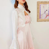 Ballerina Pink Satin Midi Dress paired with a white lace bolero, highlighting the ruched neckline and soft pastel aesthetic in a vintage setting.