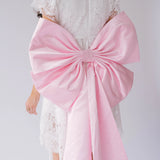 Pink fabric bow on a white lace mini dress featuring the Ballet Pink Grand Bow Sash Belt