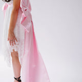 Woman wearing a white lace mini dress featuring the Ballet Pink Grand Bow Sash Belt
