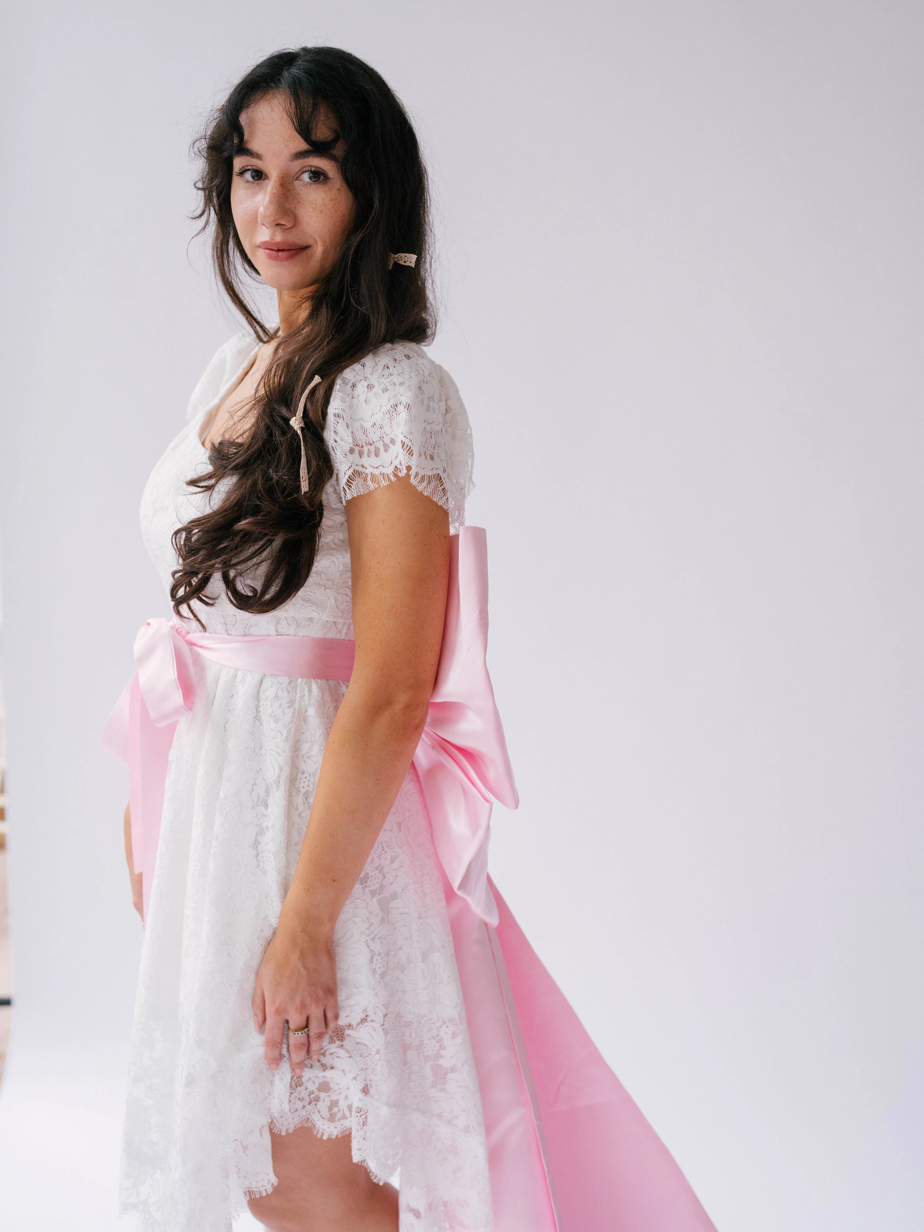White lace dress with Ballet Pink Bow Sash Belt for a stylish look.