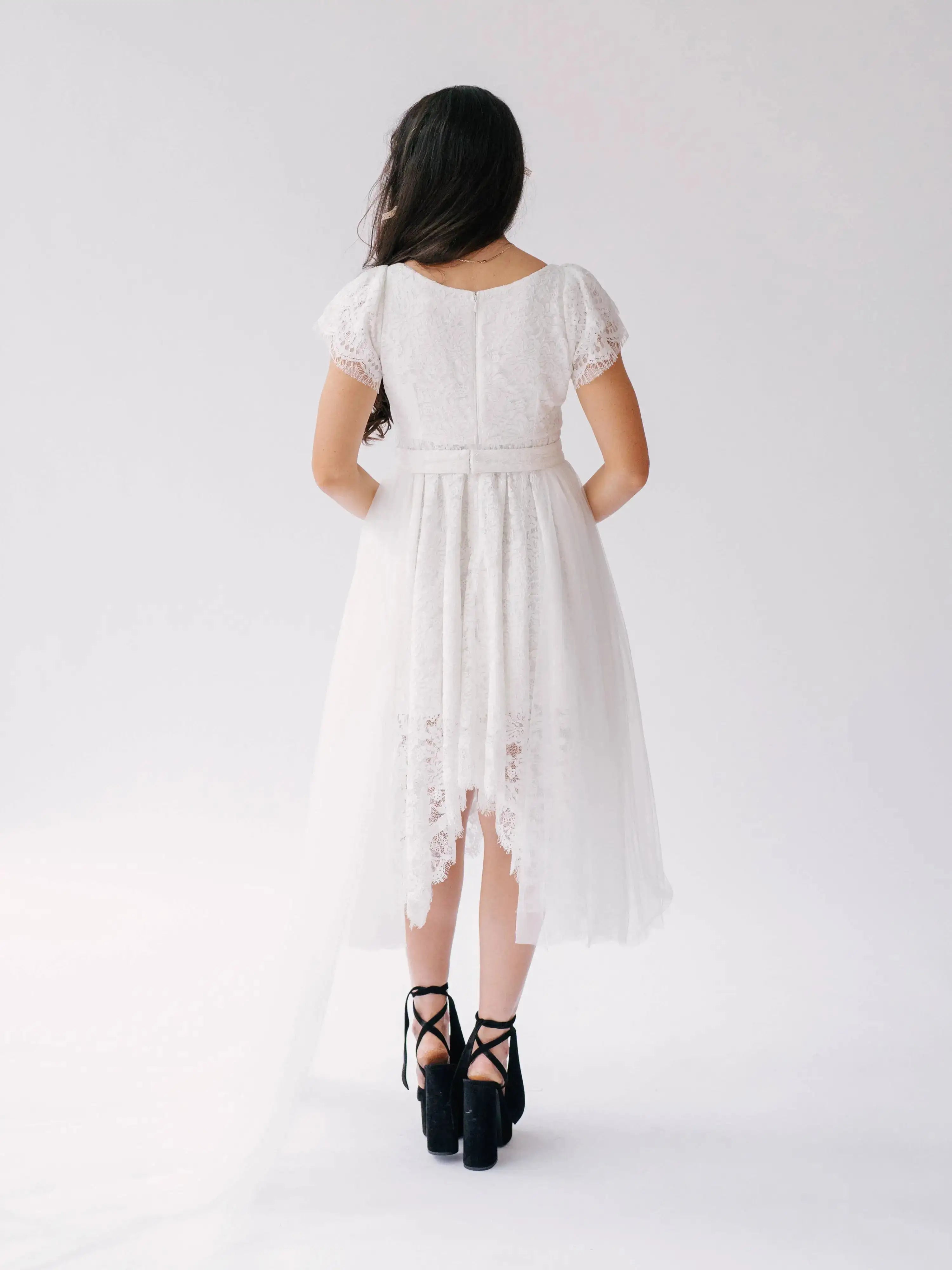 Back view of Belladonna Lace Dress showing lace bodice, flutter sleeves, and long tulle train cascading from high-low hem.