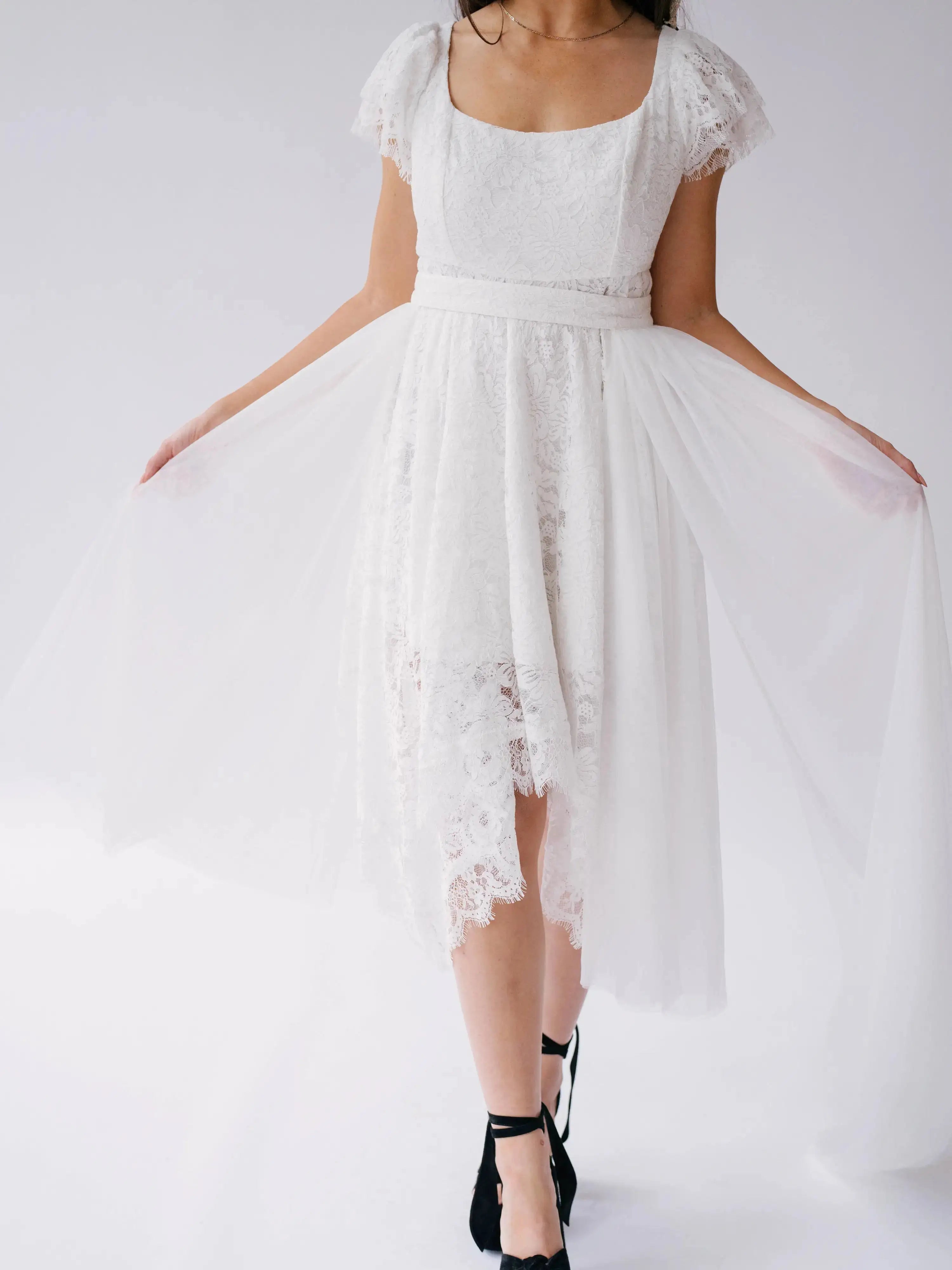 Front detail of Belladonna Lace Dress with sheer tulle overlay and scalloped lace hem, styled for modern bridal wear.