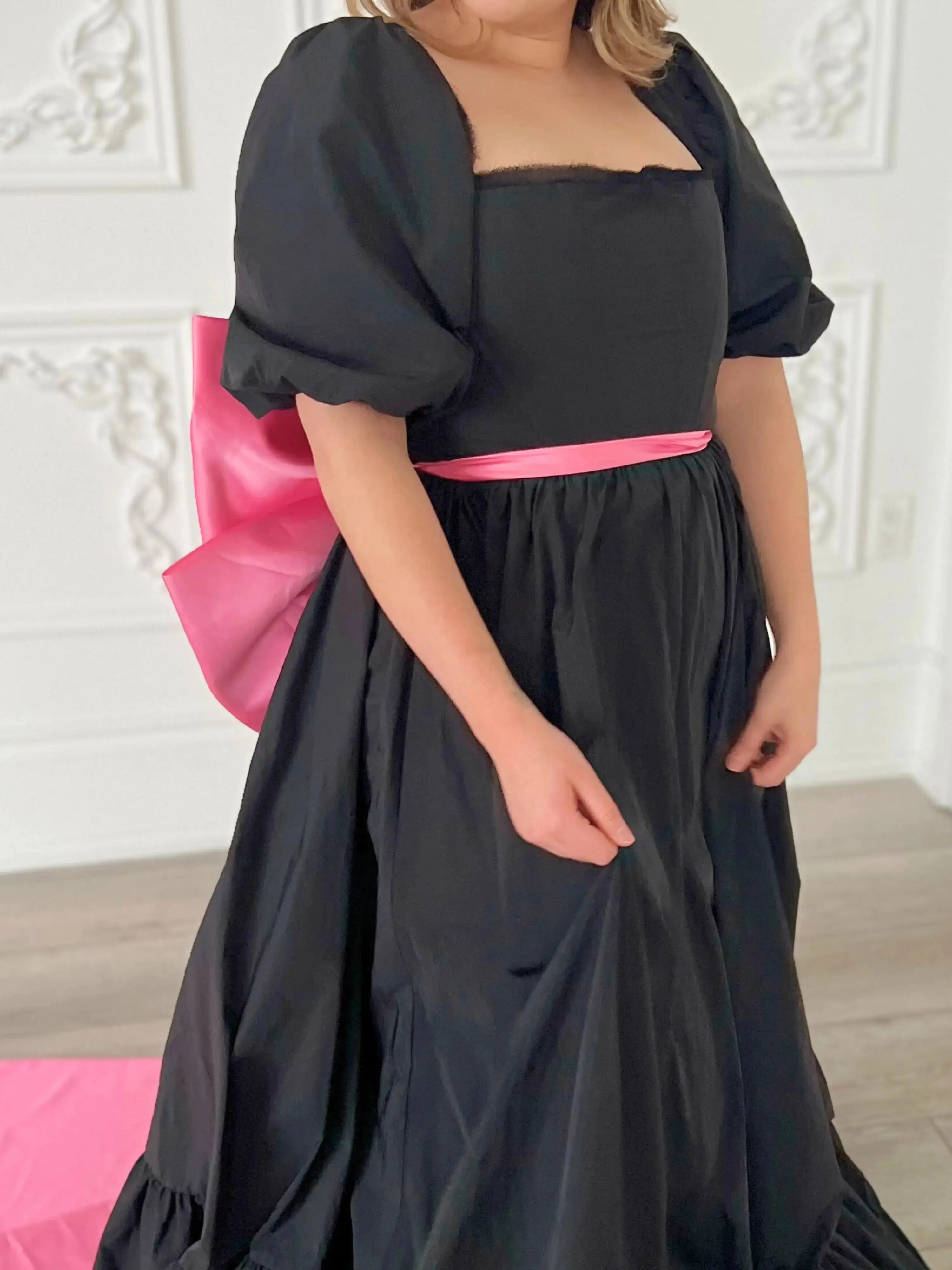 Bubblegum Pink Bow Belt wrapped around waist of black puff-sleeve dress, showcasing adjustable fit and bold color contrast.