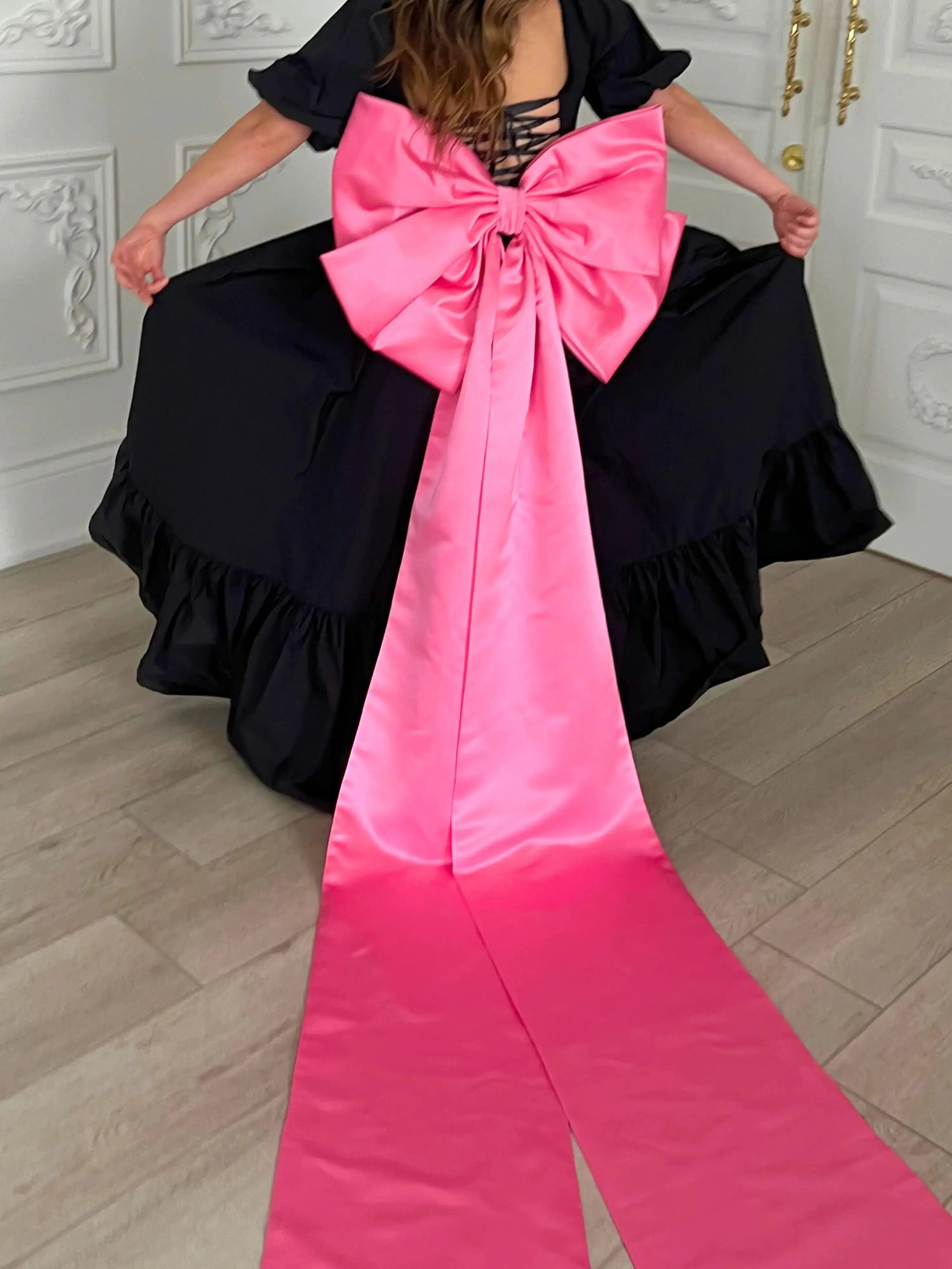 Bubblegum Pink Bow Belt featuring dramatic oversized bow and extended satin tails flowing down the back of a black gown.