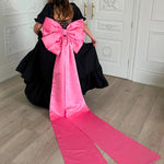 Bubblegum Pink Bow Belt with sculpted bow and sweeping tails styled on a voluminous black dress, ideal for Winter Drop 2023 fashion.