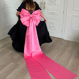 Bubblegum Pink Bow Belt with sculpted bow and sweeping tails styled on a voluminous black dress, ideal for Winter Drop 2023 fashion.