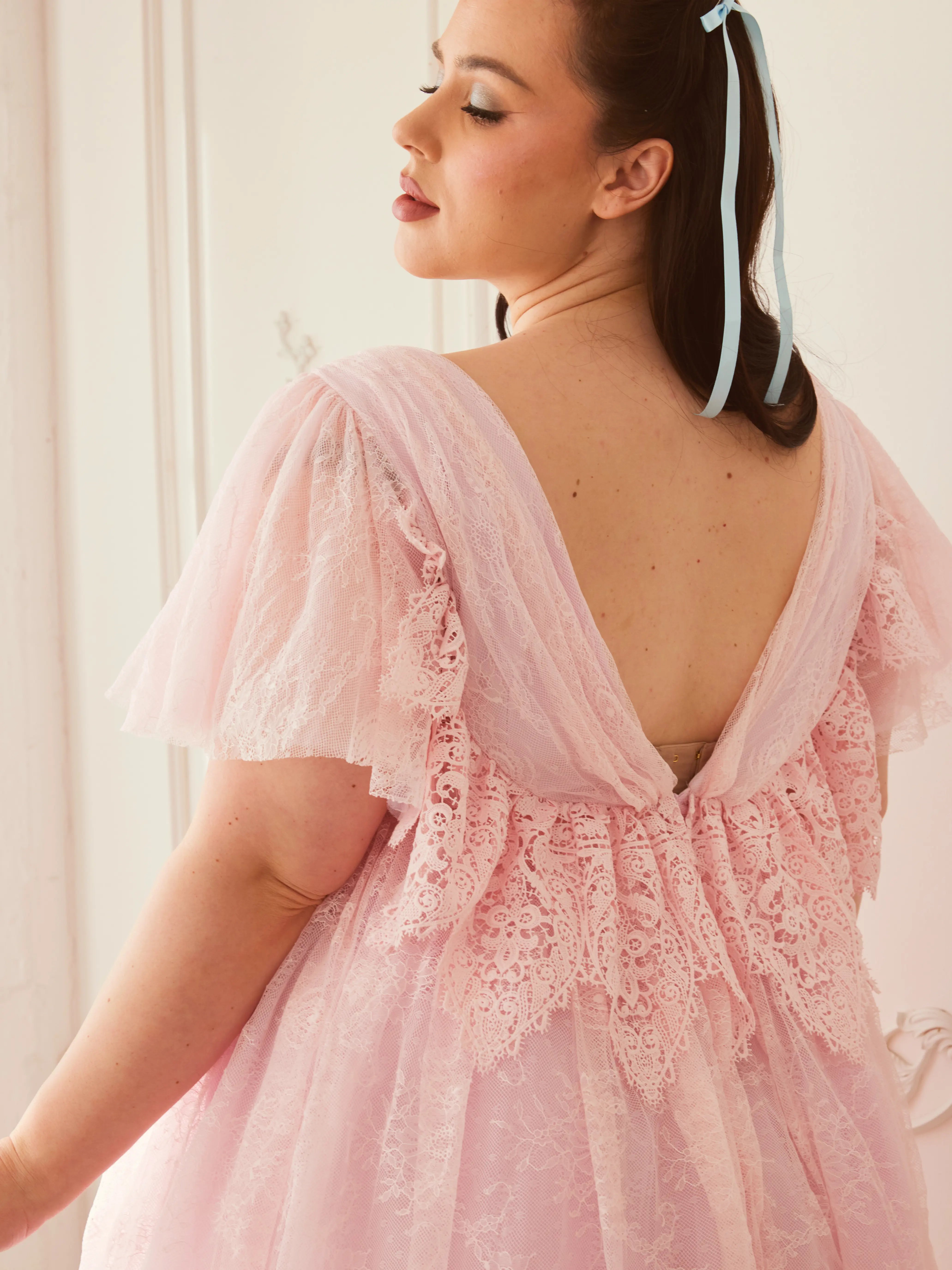 Back view of the Cherub Pink Lace Dress featuring intricate lace detailing and a low V-back design for a dreamy fairytale look.