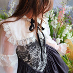 Woman wearing The Ciela Shrug Top featuring lace trim collar and black ribbon tie, overtop a corset mini dress