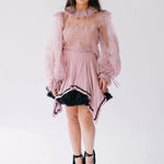Eleanor Dusty Pink Lace Blouse with sheer puff sleeves, floral appliqués, and ruffle collar, styled with a flared skirt for romantic layering.