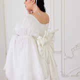 the Ivory Bridal Grand Bow Belt styled on a puff-sleeve mini wedding dress, highlighting its dramatic bow and cascading satin train.