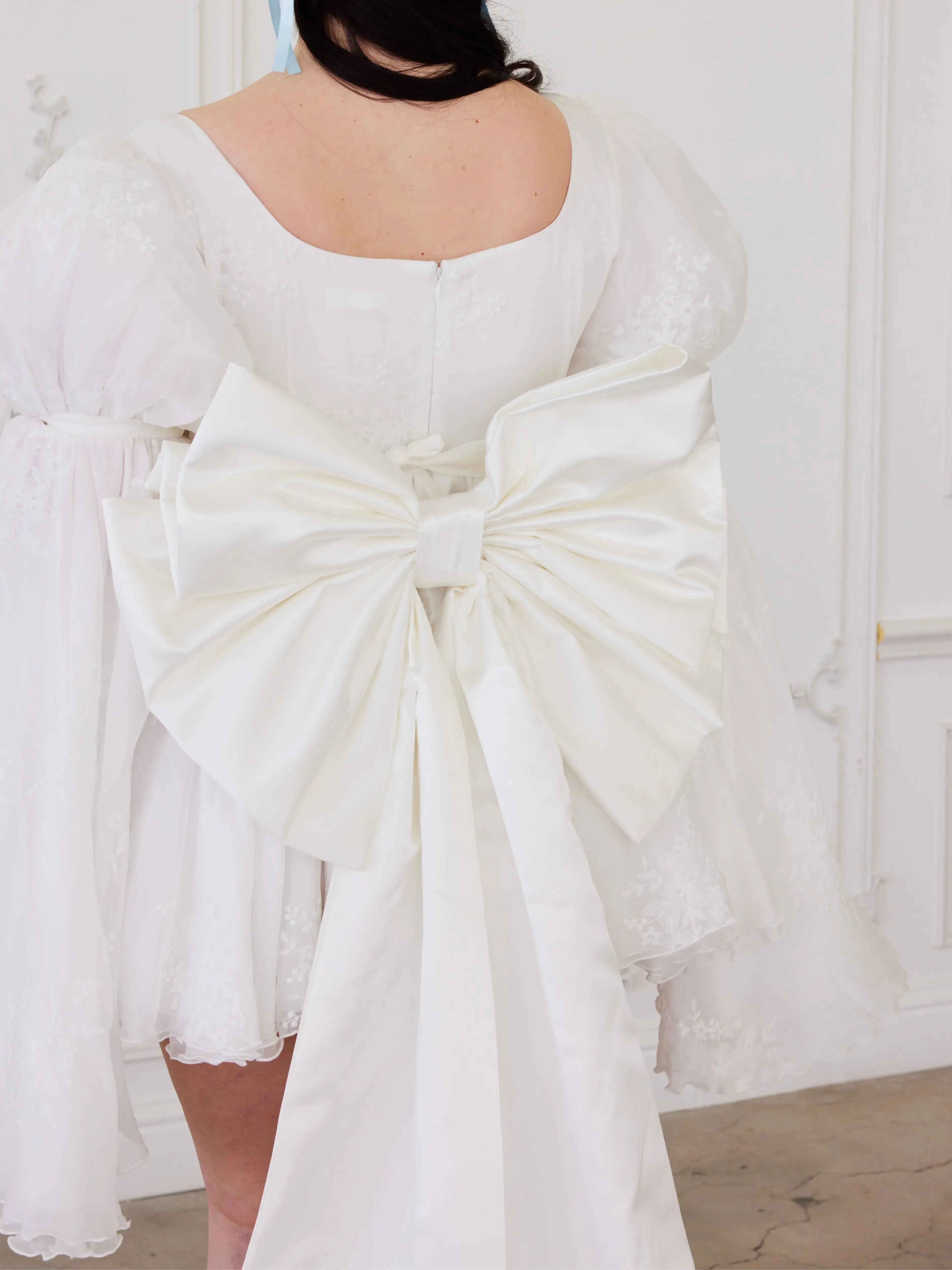 Detailed view of the Ivory Bridal Grand Bow Belt's oversized satin bow and flowing train, ideal for modern wedding ensembles.