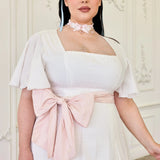 The Ivory Cloud Cotton Day Dress with soft pink waist bow and flutter sleeves, showcasing textured Swiss dot fabric for a vintage-inspired look.