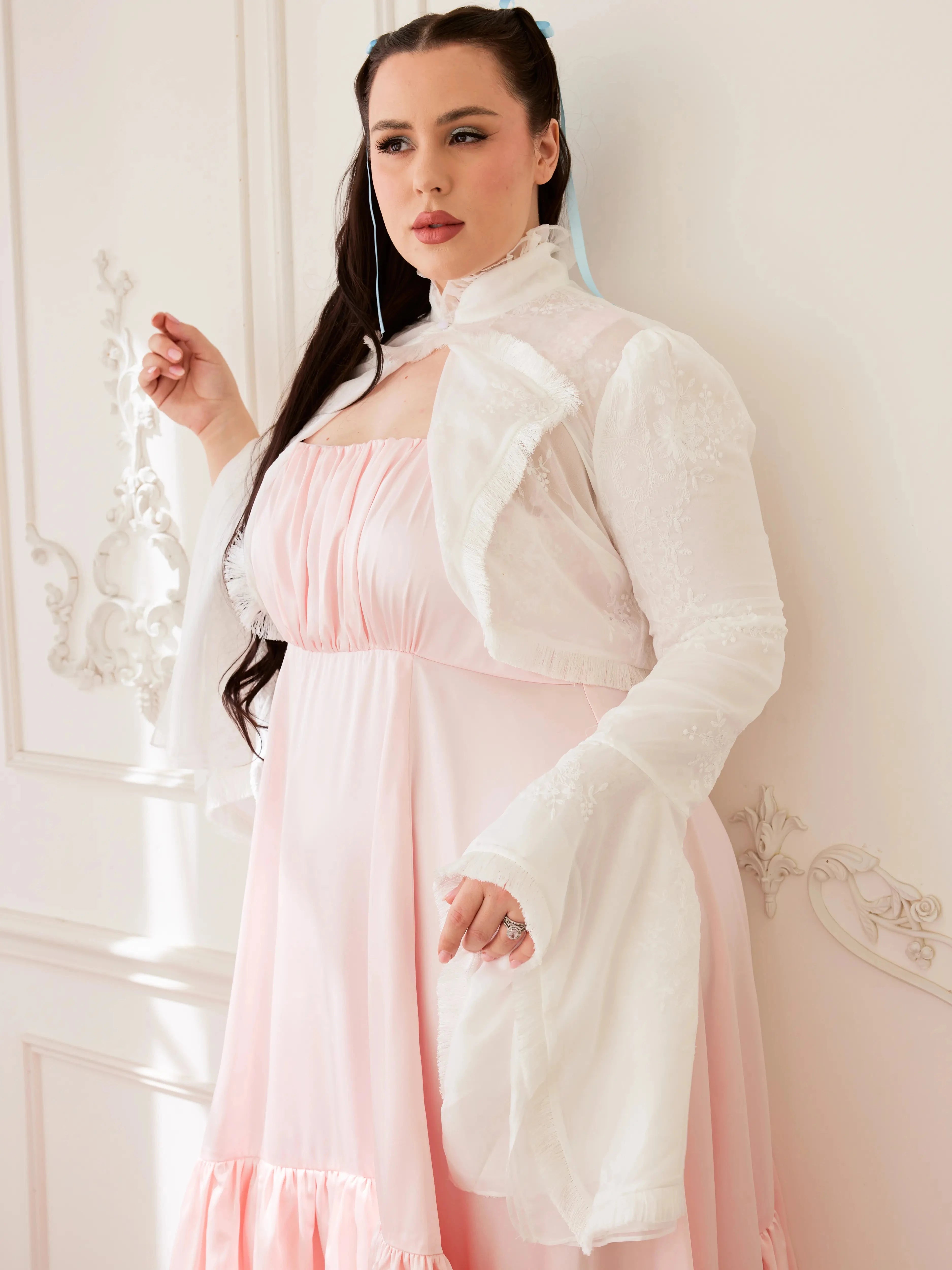 Model poses in the Ivory Lady Elizabeth Bolero Jacket, featuring floral lace design, ruffled collar, and soft bell sleeves in a vintage setting.