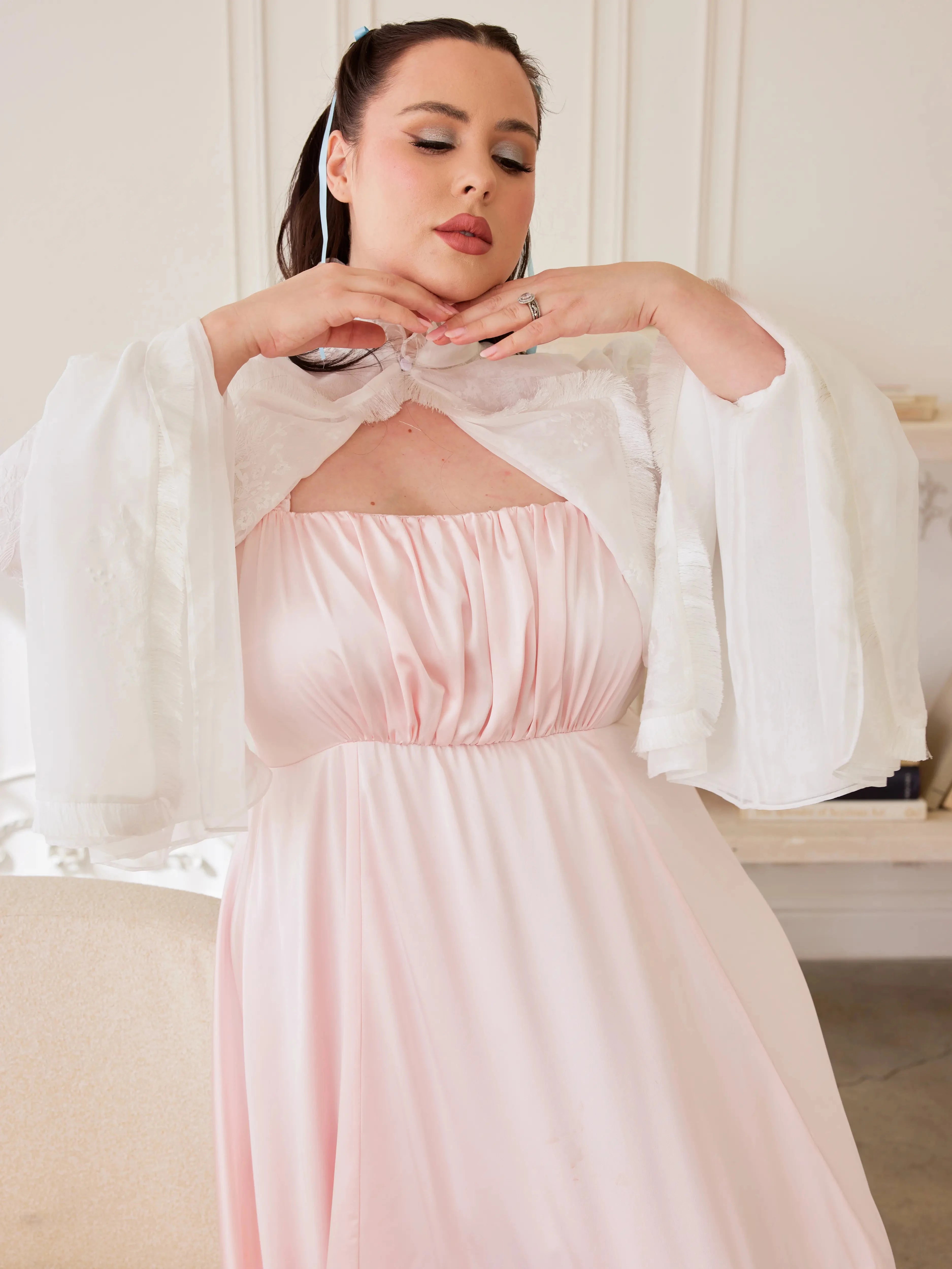 Ivory Lady Elizabeth Bolero Jacket featuring ruffled lace trim and flowing bell sleeves over a blush pink dress.
