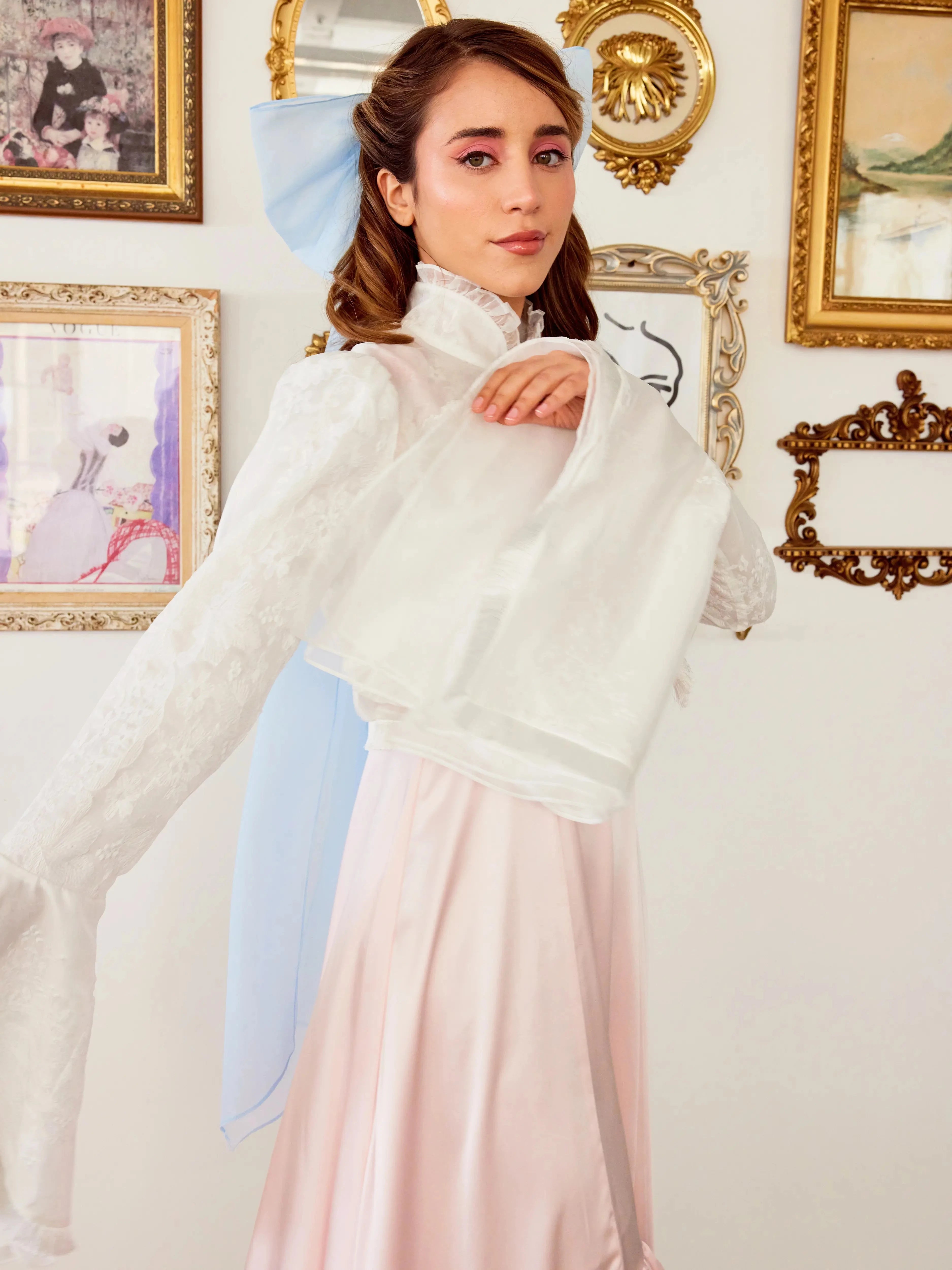 Back view of the Ivory Lady Elizabeth Bolero Jacket with flowing bell sleeves and embroidered lace, styled with a pastel pink dress.