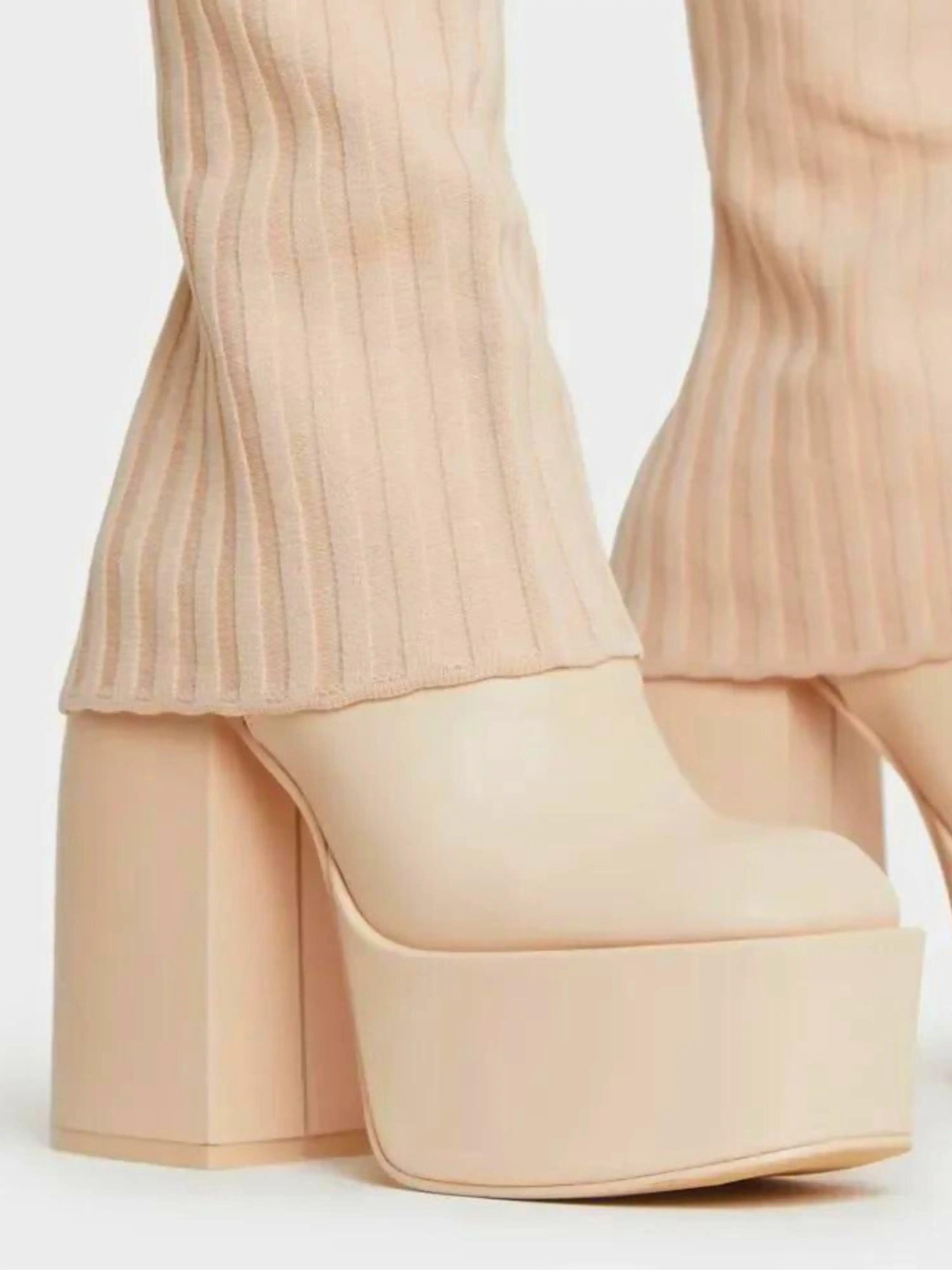 Nude-colored platform shoes with chunky heels and ribbed pants legs visible above them.