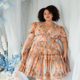 Ode To Jove Grace Day Dress styled in a floral setting, highlighting its puff sleeves and romantic silhouette. Perfect for garden parties or daytime events.