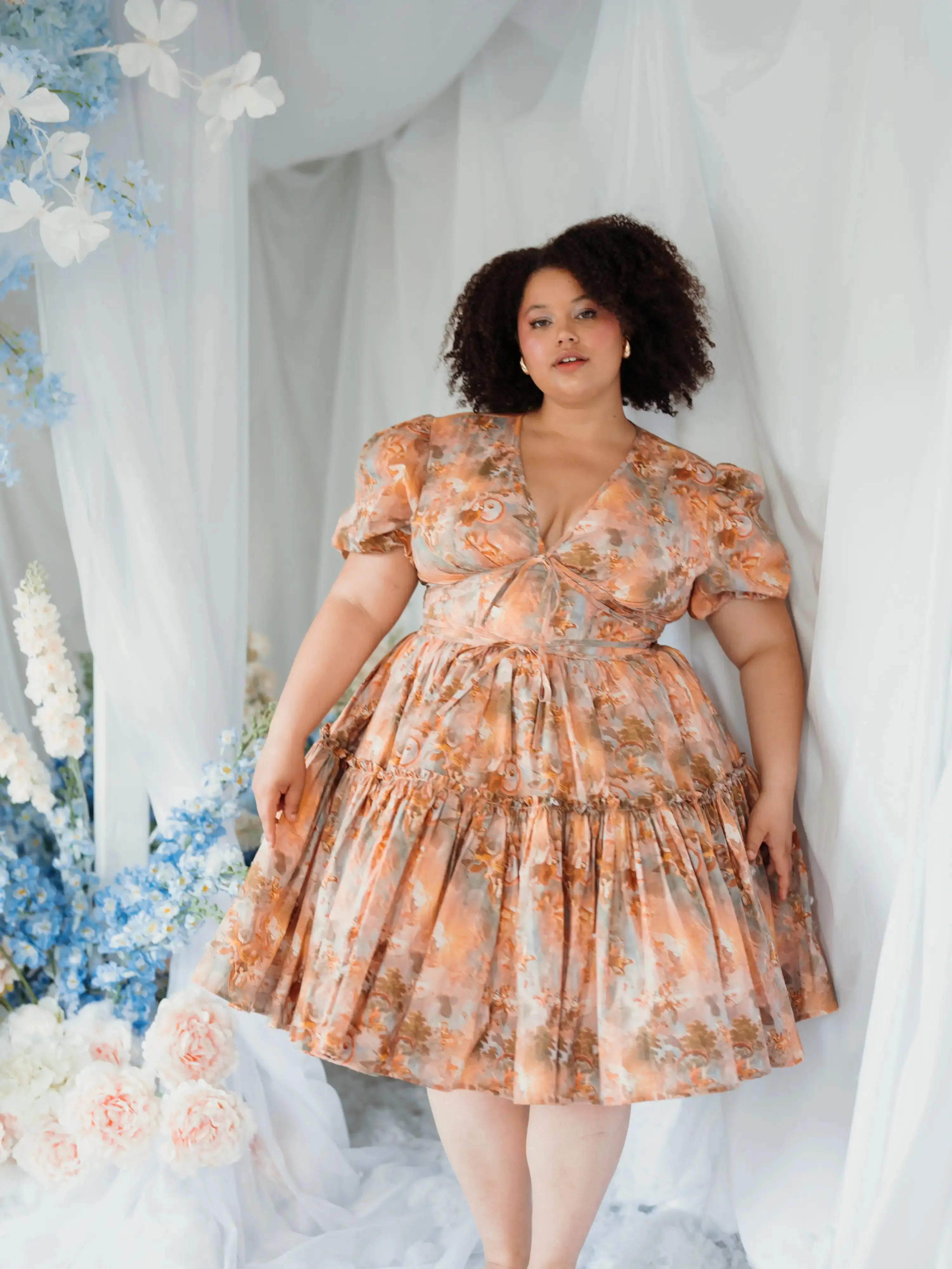 Ode To Jove Grace Day Dress styled in a floral setting, highlighting its puff sleeves and romantic silhouette. Perfect for garden parties or daytime events.