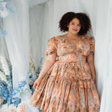 Ode To Jove Grace Day Dress styled in a dreamy floral setting, emphasizing its romantic puff sleeves and fresco print. Softly structured and lined.