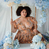 Ode To Jove Grace Day Dress in cotton with fresco print, puff sleeves, and full skirt styled on a swing with floral decor. Romantic and whimsical look.