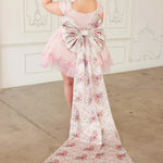 the Rosewater Grand Bow Belt with oversized floral bow and extended satin tails, styled on a pink lace dress for whimsical elegance.