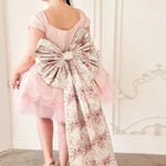 the Rosewater Grand Bow Belt with voluminous floral bow and extended satin tails, paired with a pink tulle dress and floral heels.