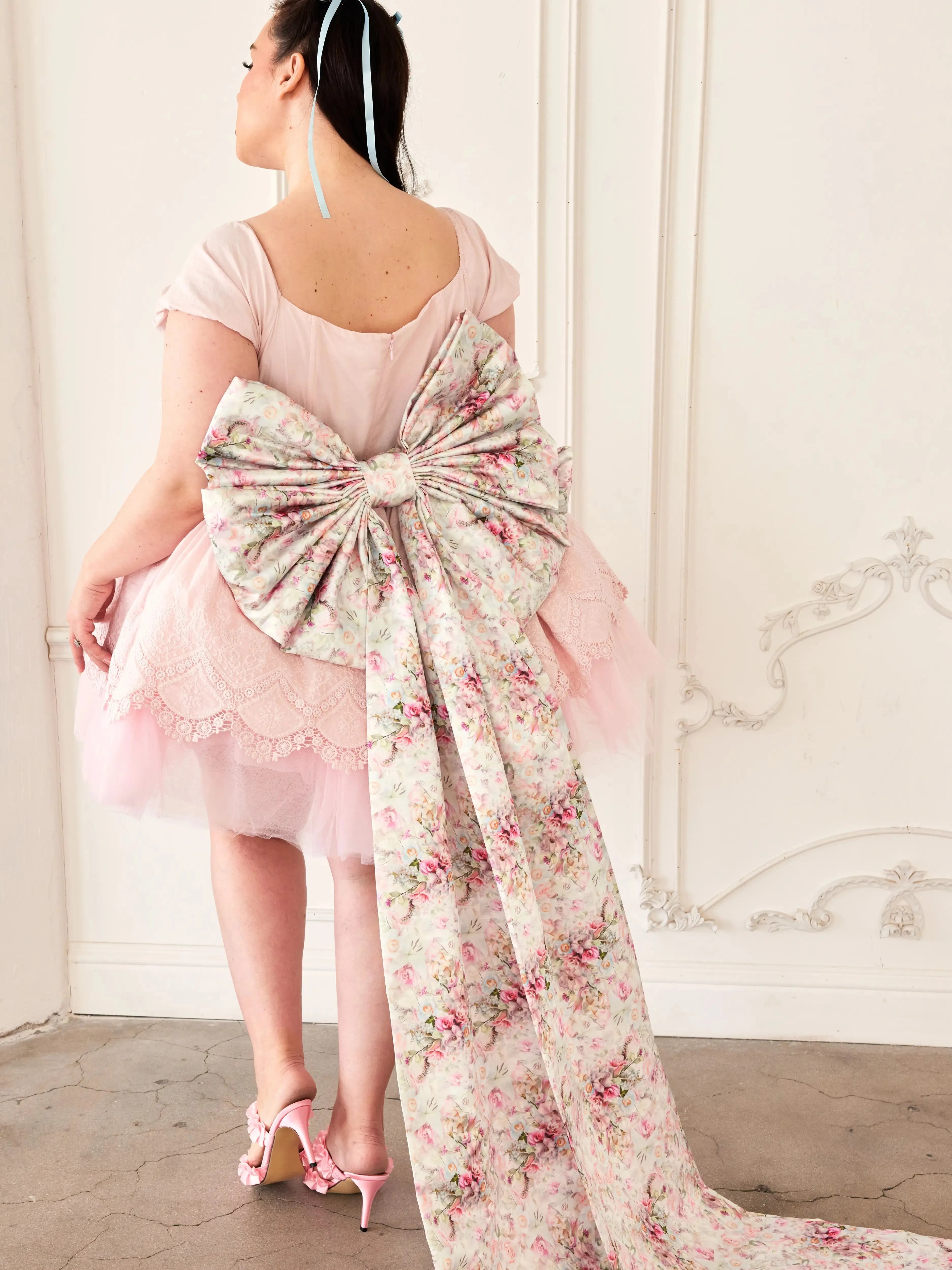 the Rosewater Grand Bow Belt with voluminous floral bow and extended satin tails, paired with a pink tulle dress and floral heels.