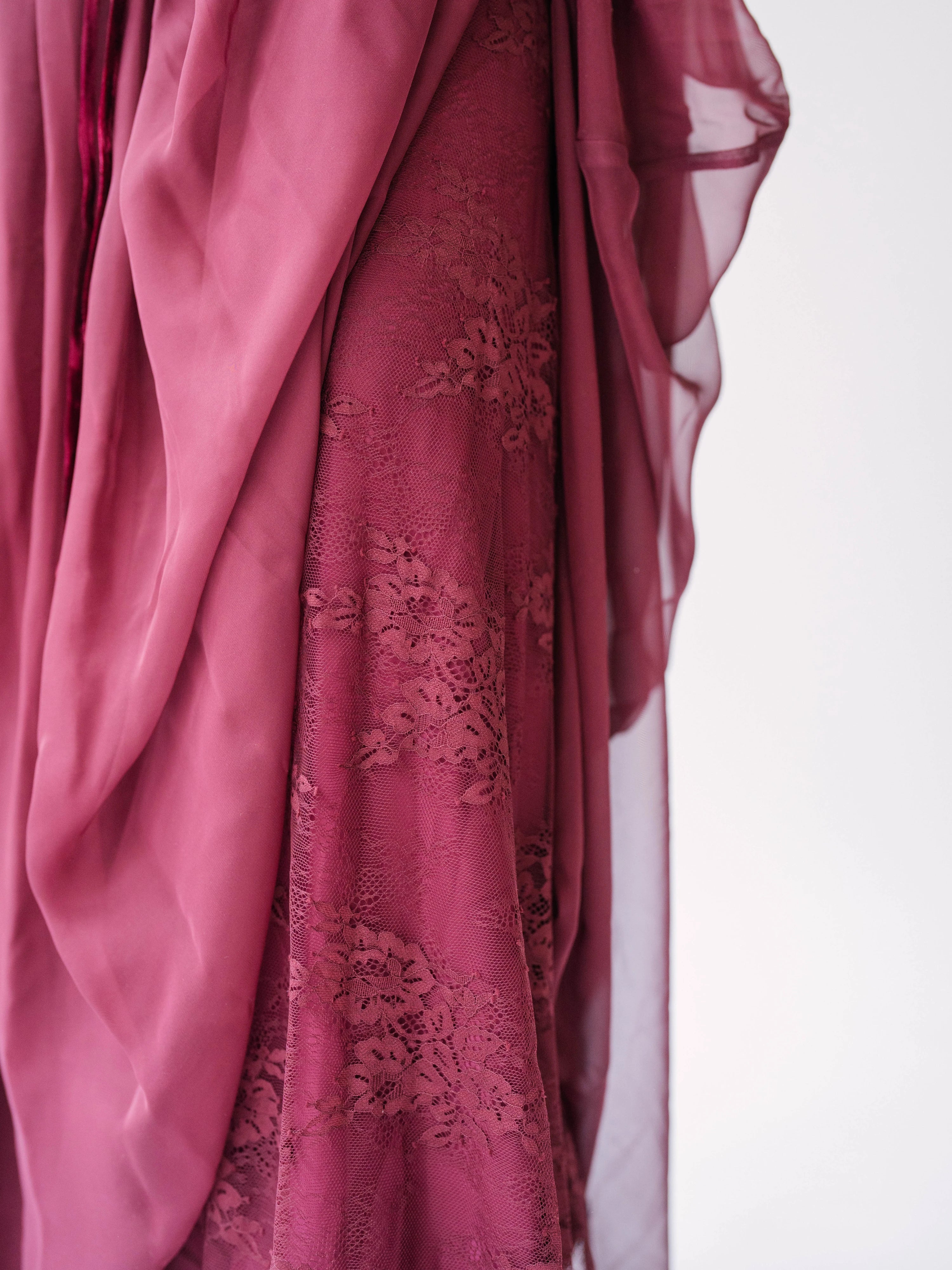 Scarlet rose-colored chiffon fabric with delicate floral embroidery layer draping underneath in soft folds.