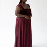 The Scarlet Red Scorned Lovers Gown is a corset maxi dress with a square neckline and multilayered skirt with floral embroidery on the inner layers.