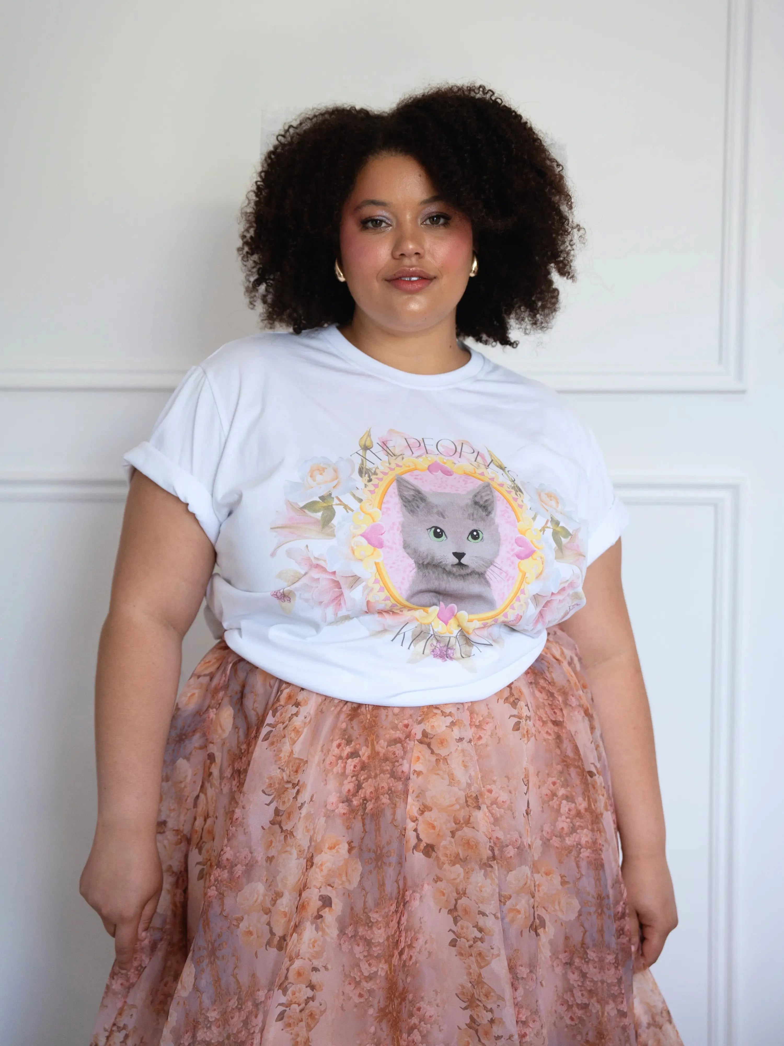 The Princess Kitten Tee styled casually with a floral skirt, highlighting the central kitten artwork and rolled sleeves for a relaxed fit.