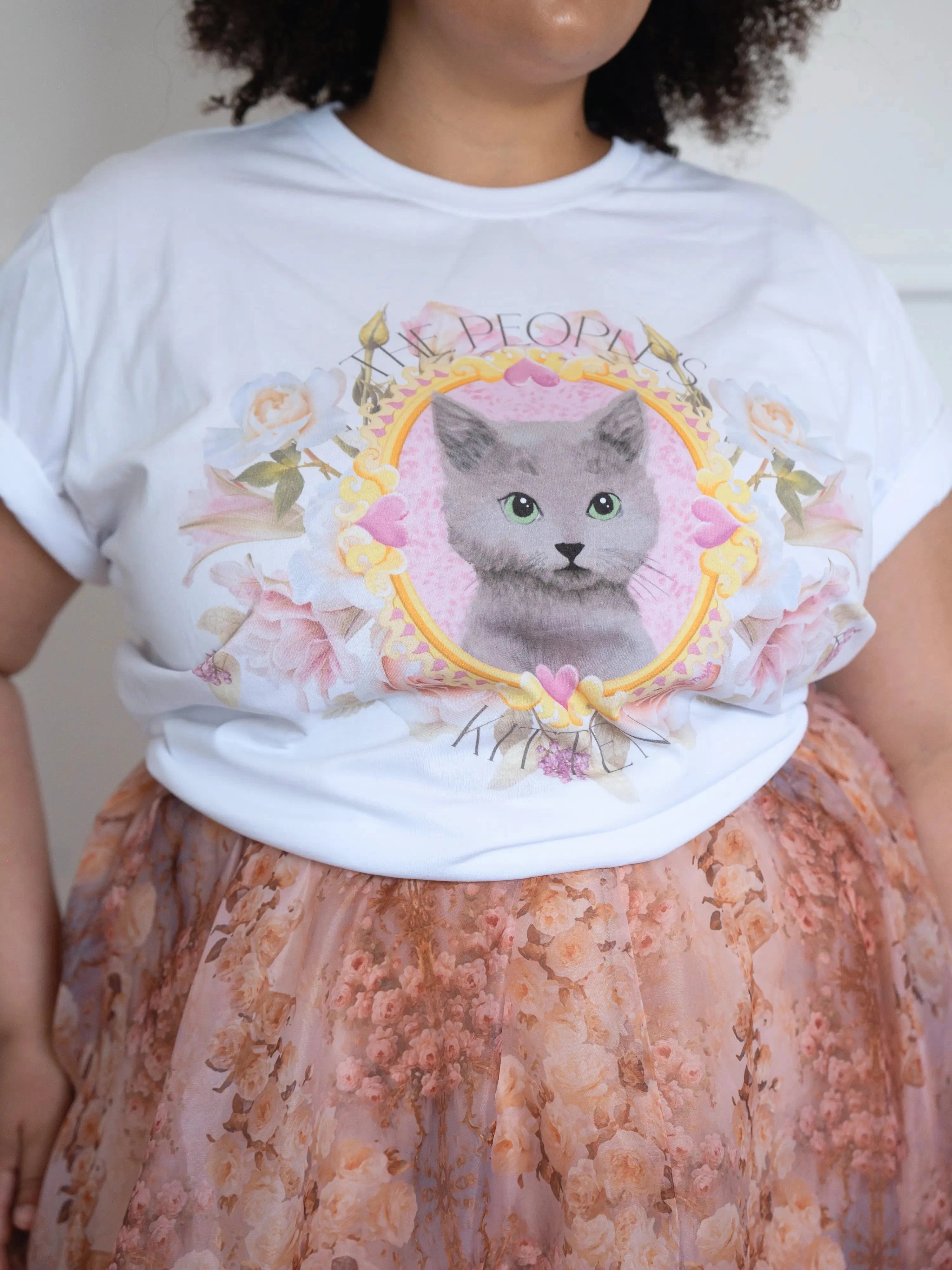 Close-up of The Princess Kitten Tee highlighting the detailed kitten illustration framed by pastel florals and gold accents.