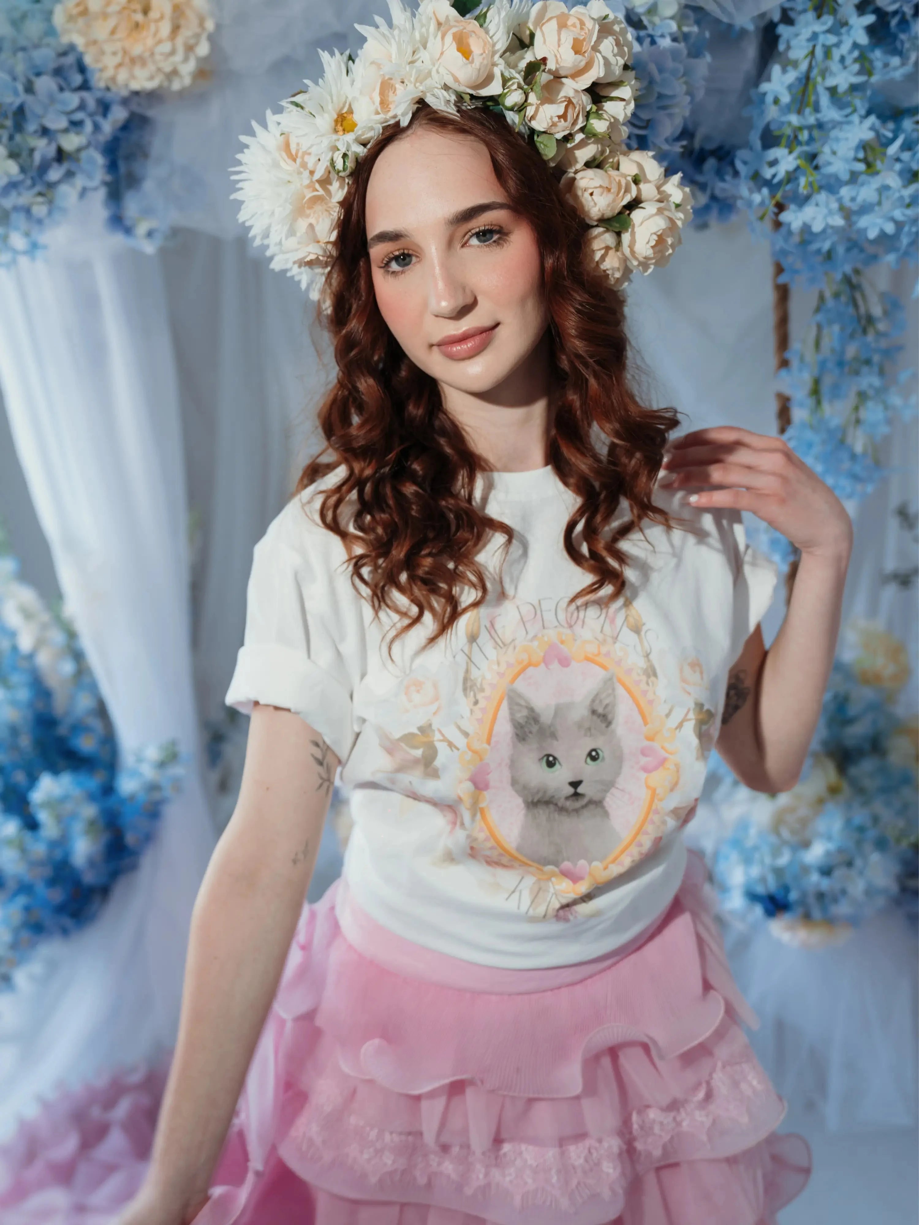 Model wearing The Princess Kitten Tee in a floral-themed setting, styled with a flower crown and pink ruffle skirt for a whimsical look.