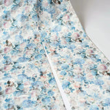 close up of the Wildbloom Grand Bow Belt's exclusive floral satin fabric with soft blue, pink, and cream tones in a romantic print.