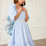 Front view of the Wildbloom Grand Bow Belt cinching a pastel blue dress, showcasing the floral waistband and voluminous silhouette.