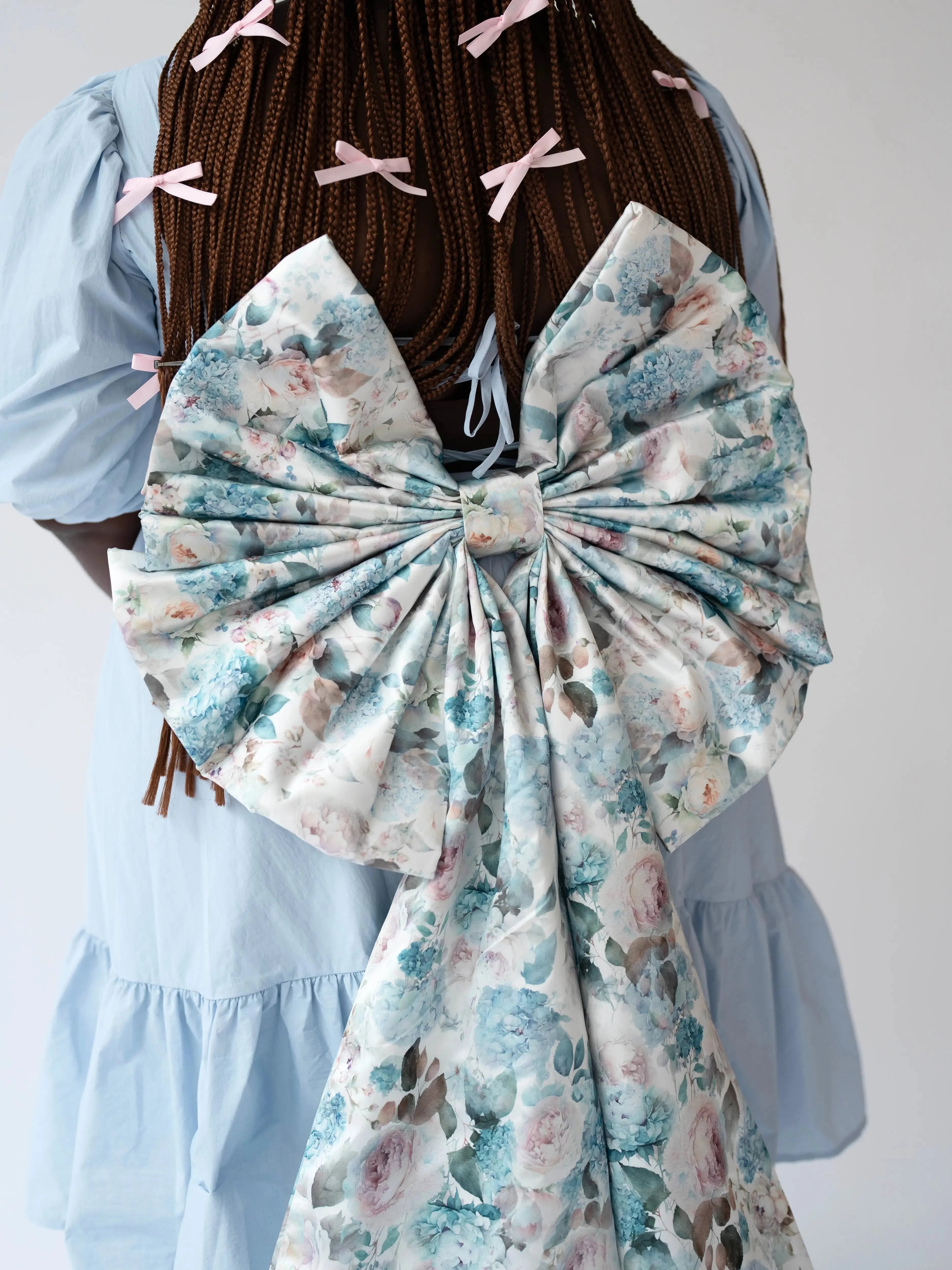 Zoomed-in back view of the Wildbloom Grand Bow Belt on braided hair model, emphasizing the structured floral bow and elegant draping.