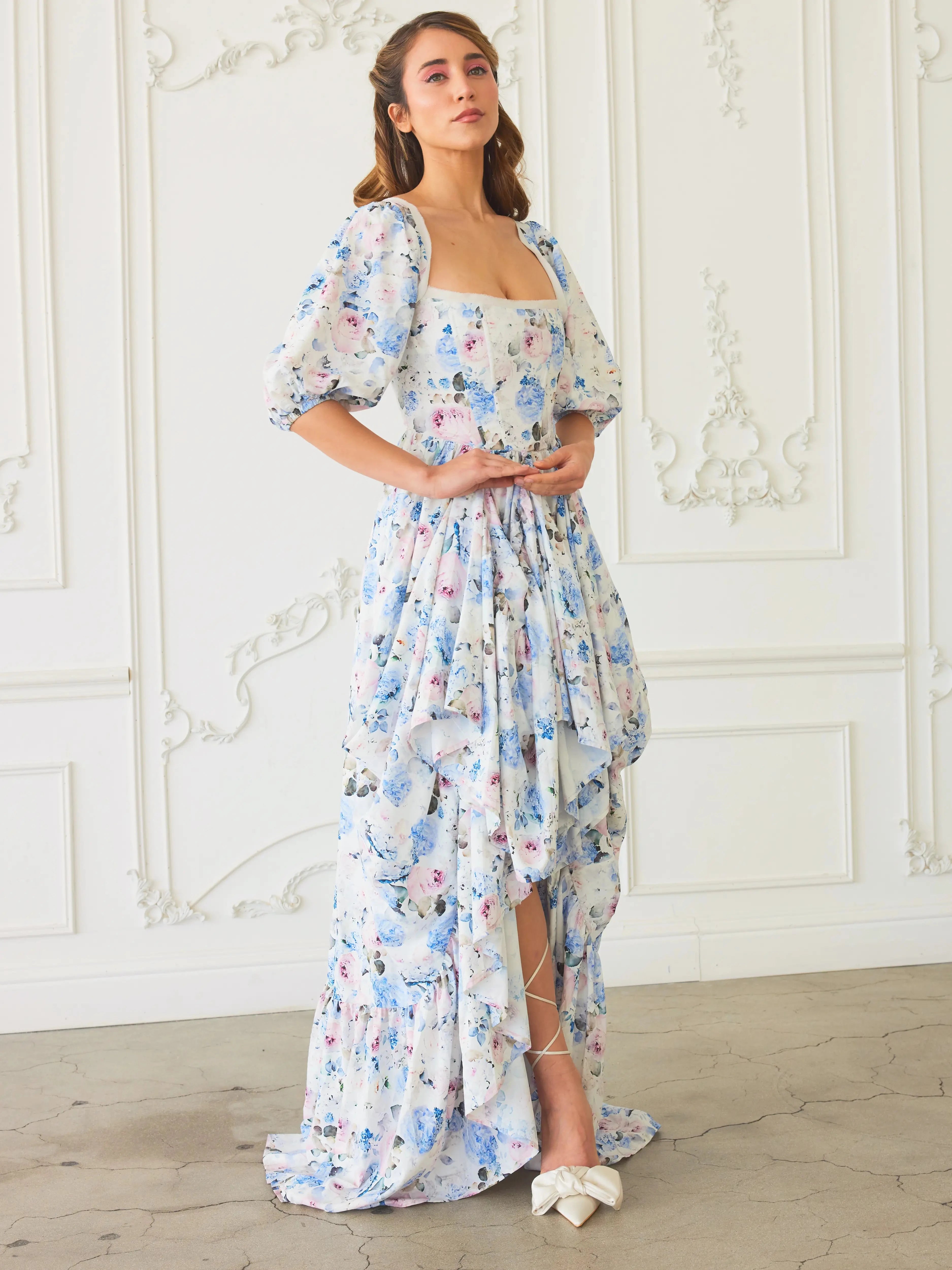The Wildbloom Josephine Ball Gown, a floral Ball Gown with a high-low bustle skirt and corset bodice, styled with bow heels.