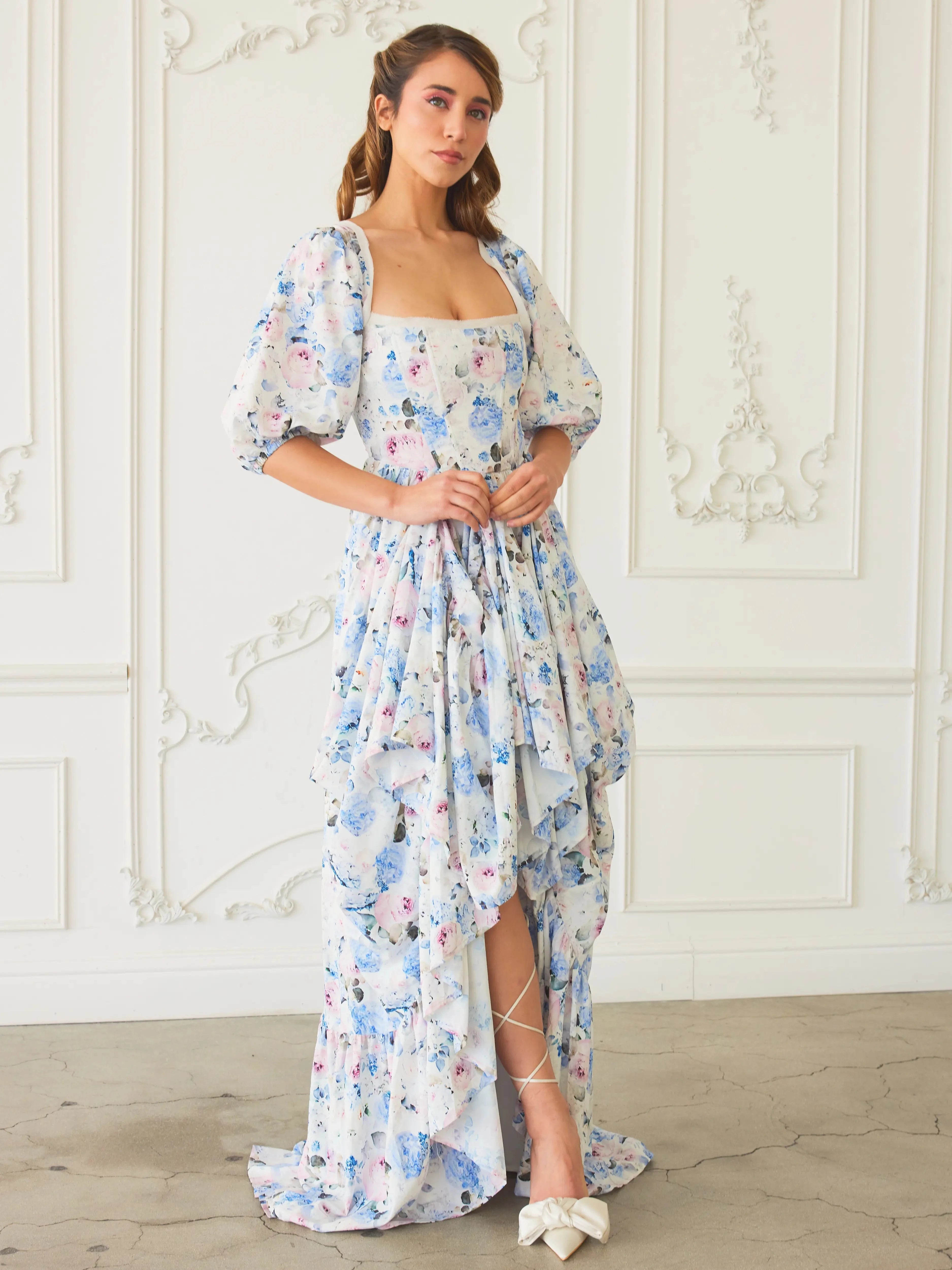Front view of The Wildbloom Josephine Ball Gown showcasing a high-low hem and corset bodice, styled with white heels.