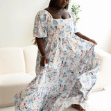 The Wildbloom Josephine Ball Gown, a floral Ball Gown with corset lacing and puff sleeves, modeled in a lounge setting.