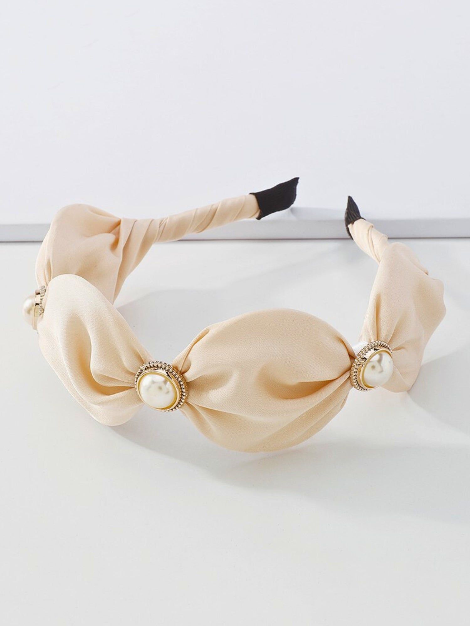 The Adorned Pearl Headband in ivory satin with large pearl and gold embellishments, perfect for elegant hair styling. Ideal for formal or bridal looks.