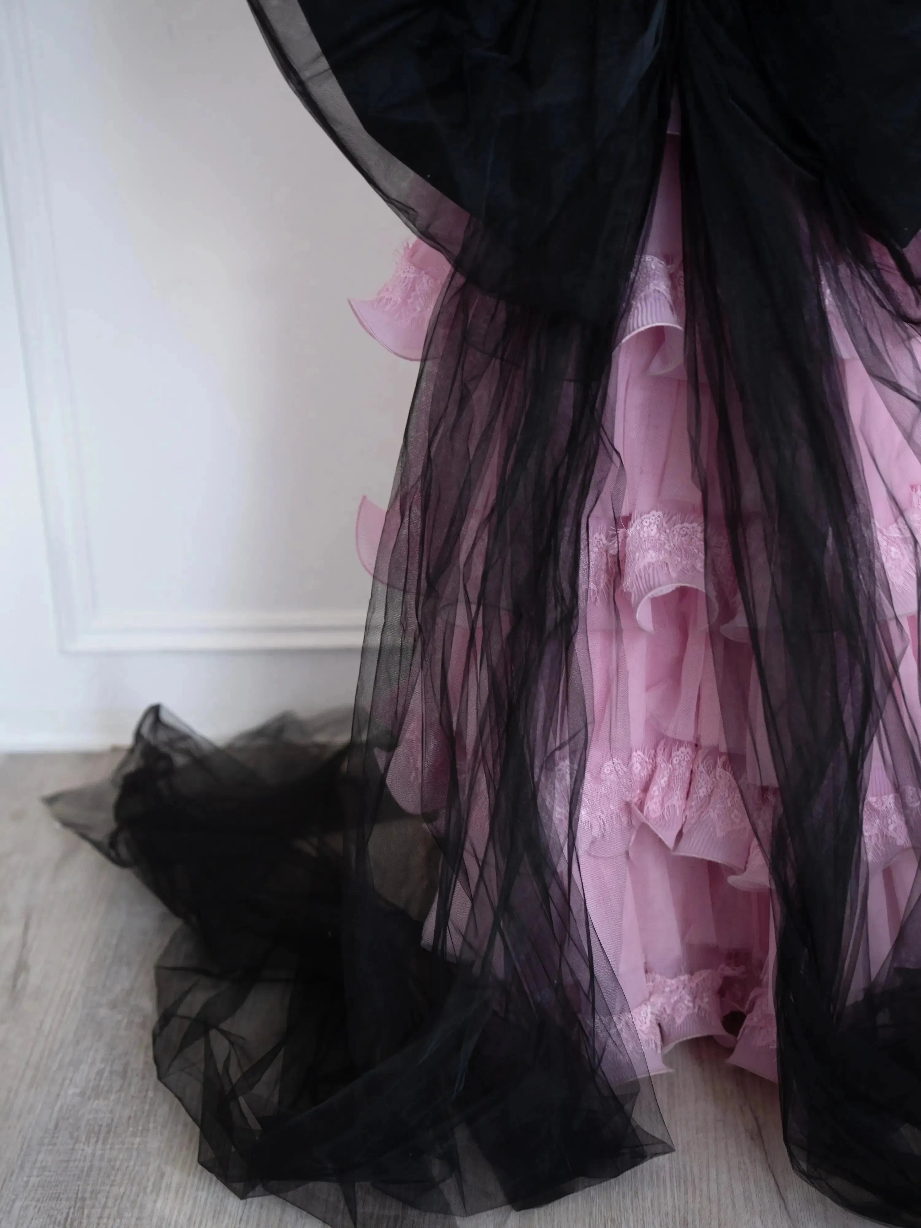 Close-up of The Black Swan Grand Bow Belt's flowing black tulle tails cascading over a pink tiered lace skirt, showcasing its dramatic design.