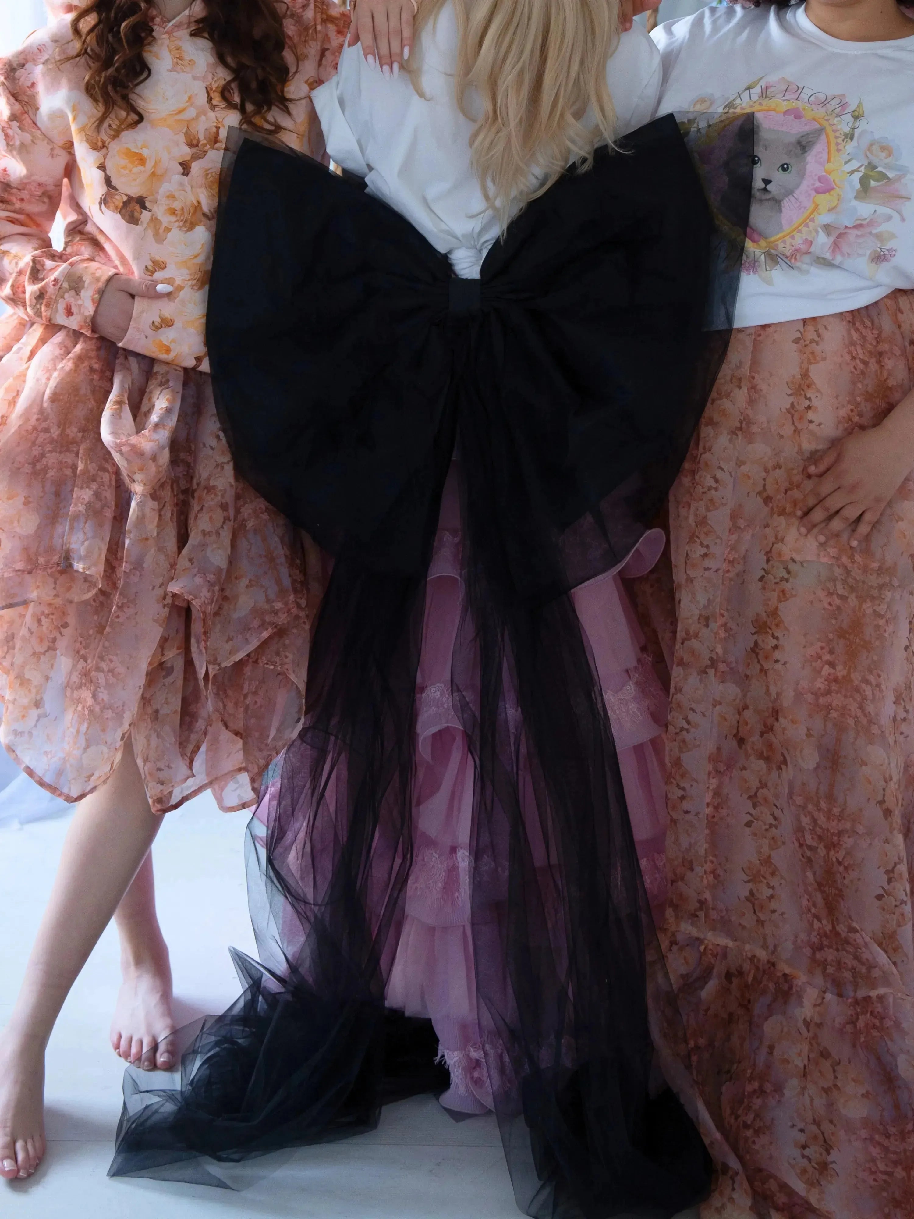 The Black Swan Grand Bow Belt styled in a dreamy ensemble, featuring oversized black tulle bow with long trailing ends over a pink ruffled skirt.
