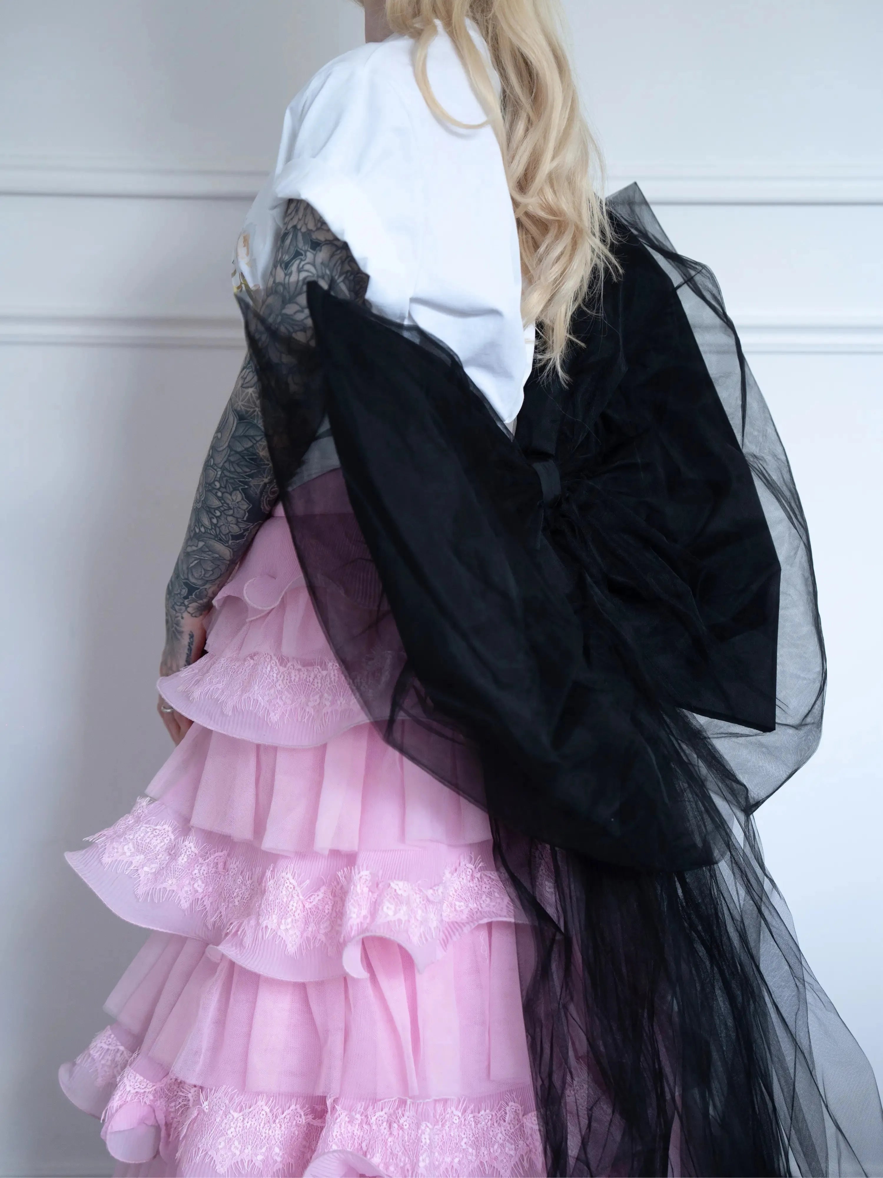 Side view of The Black Swan Grand Bow Belt highlighting its structured black satin bow and sheer tulle layers over a pink lace-tiered skirt.