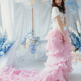 A woman wearing the dahlia pink ruffle skirt standing in front of a floral decorated backdrop.
