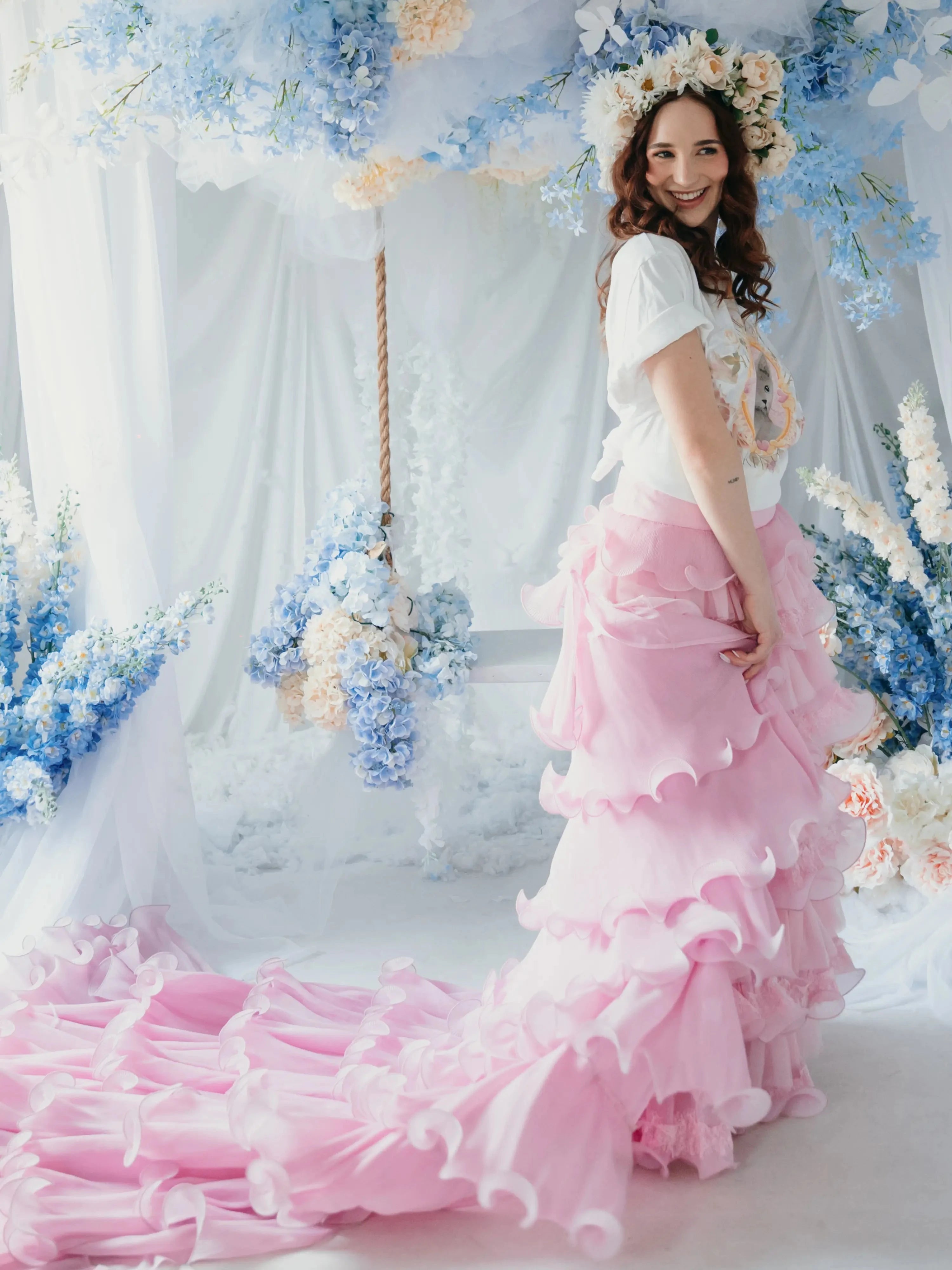 A woman wearing the dahlia pink ruffle skirt standing in front of a floral decorated backdrop.
