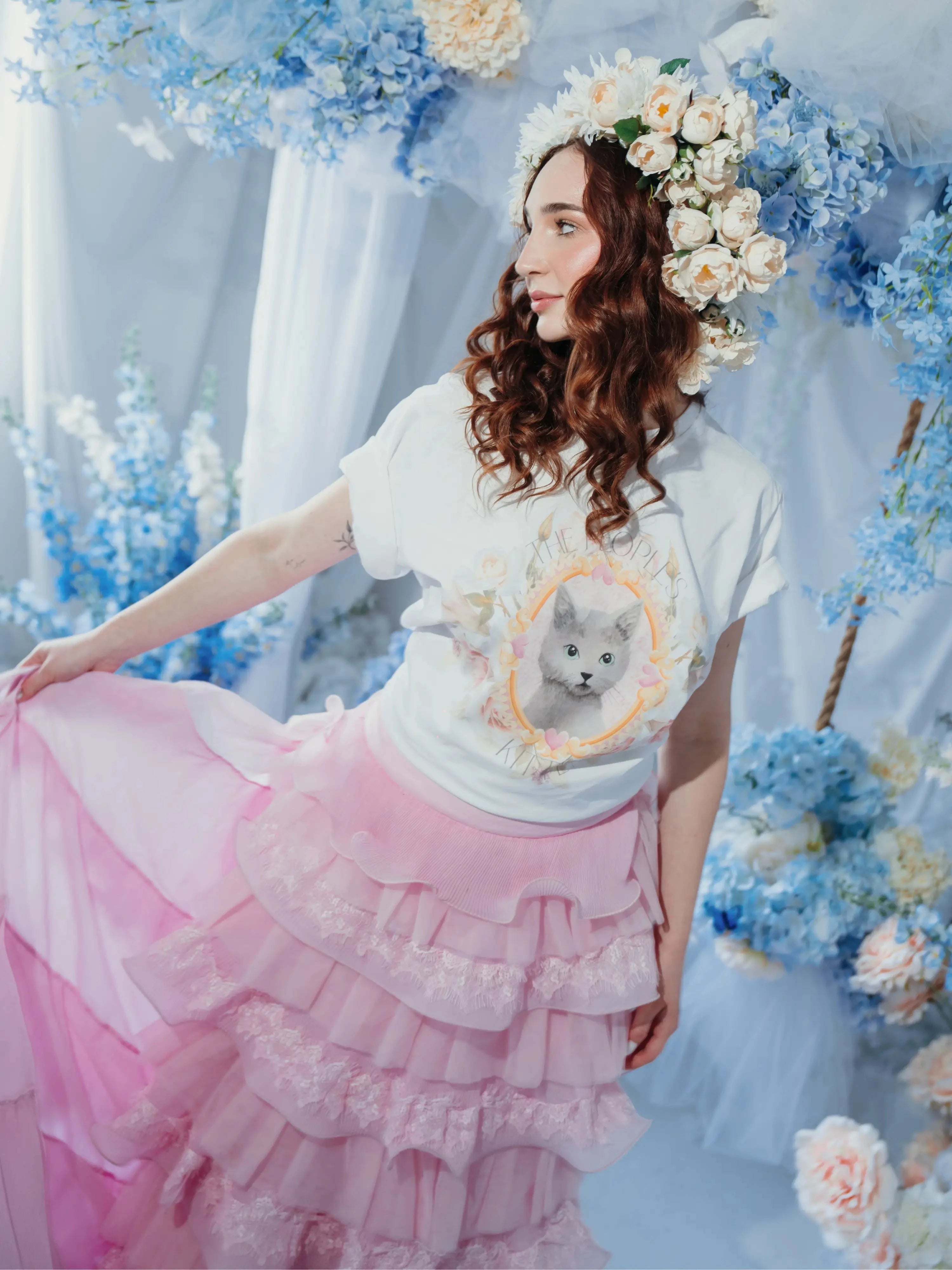 A woman wearing the dahlia pink ruffle skirt styled in a floral fantasy scene, featuring pink tulle ruffles and a flowing detachable train.